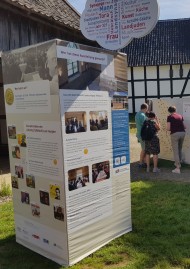 Ein Teil der Ausstellung steht auf einer Wiese vor einem Bauernhof im Freilichtmuseum Lindlar