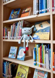 Hausgeist Levi (ein Stofftier) sitzt in einem Bücherregal im Jüdischen Museum Frankfurt